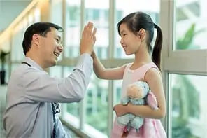 A doctor is clapping hand with a little girl