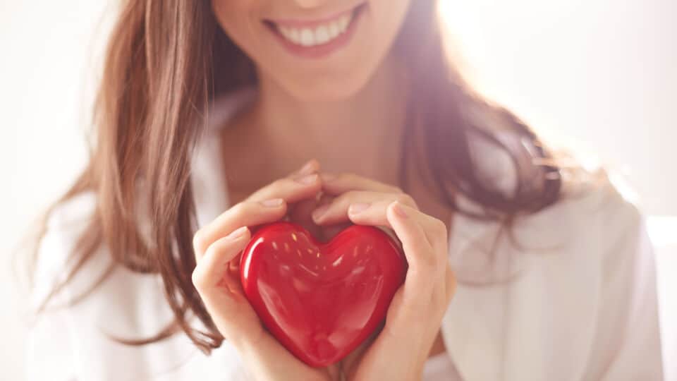 Close-up of smiling female holding red heart