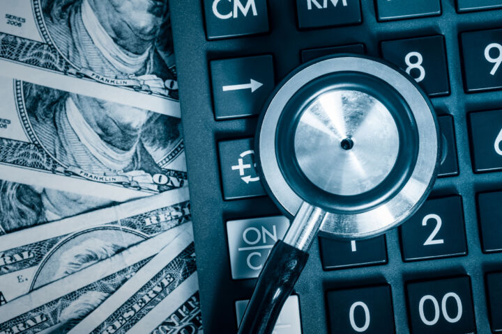 Financial analysis, audit or accounting - Stethoscope over a calculator and dollar bills toned in blue