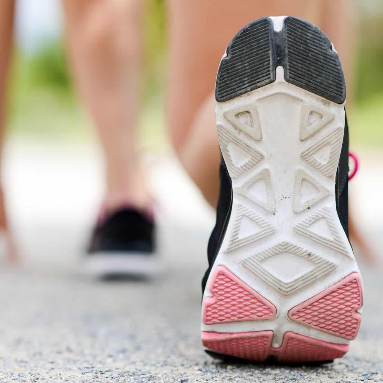 Woman feet running on road closeup on shoe